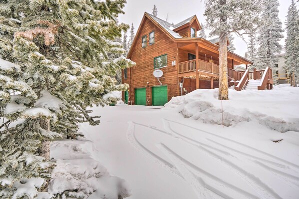 Uma cabana de madeira com varanda, rodeada por árvores cobertas de neve.