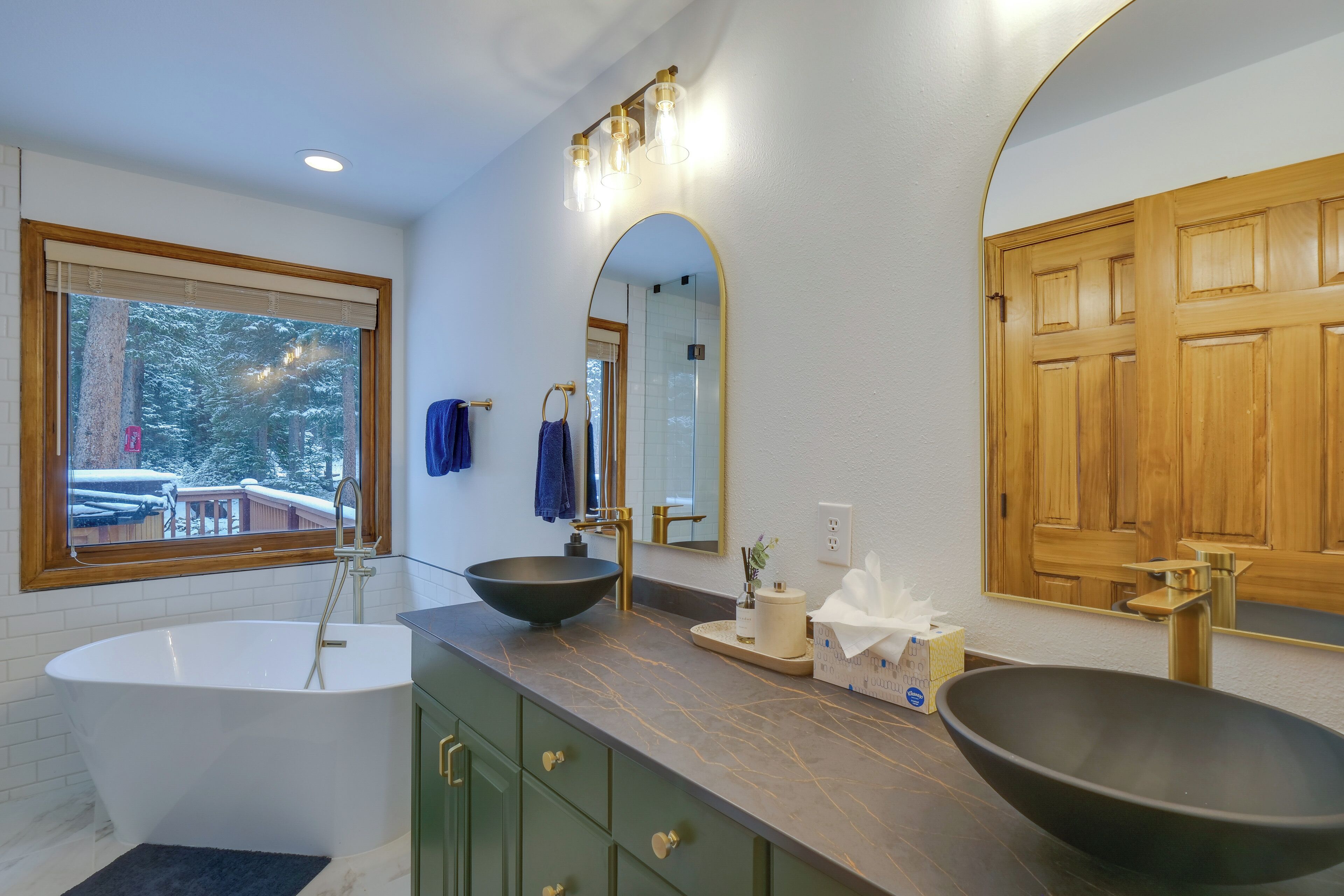 A modern bathroom with a freestanding bathtub, a vessel sink, and a large mirror.