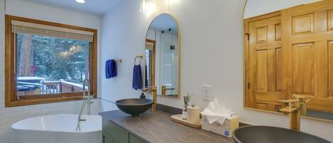 A modern bathroom with a freestanding bathtub, a vessel sink, and a large mirror.