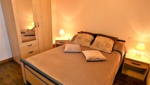 A bedroom with a bed, bedside tables, a mirror, and a wardrobe. - L'ecureuil - Soustons (SOUSTONS)