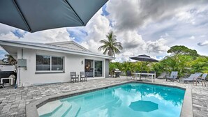 A swimming pool with a patio area, outdoor furniture, and a house with a garage. - Remodeled Naples Getaway w/ Pool ~ 1 Mi to Beach! (Naples)