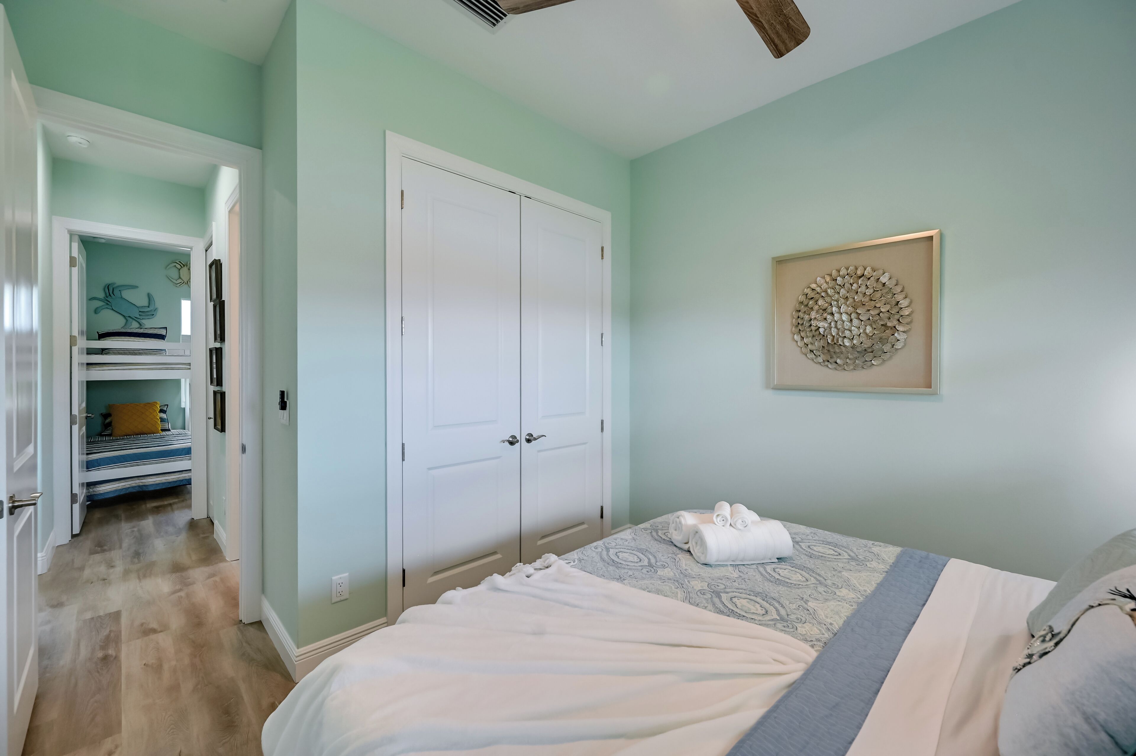 A bedroom with a bed, a wardrobe, and a hallway leading to a bathroom.
