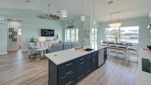 A modern kitchen with a central island, built-in appliances, and a dining area with a view. - Luxurious Canal-front Retreat w/ Game Room! (Naples)