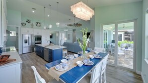 A modern kitchen with a central island, white cabinets, and stainless steel appliances. - Luxurious Canal-front Retreat w/ Game Room! (Naples)