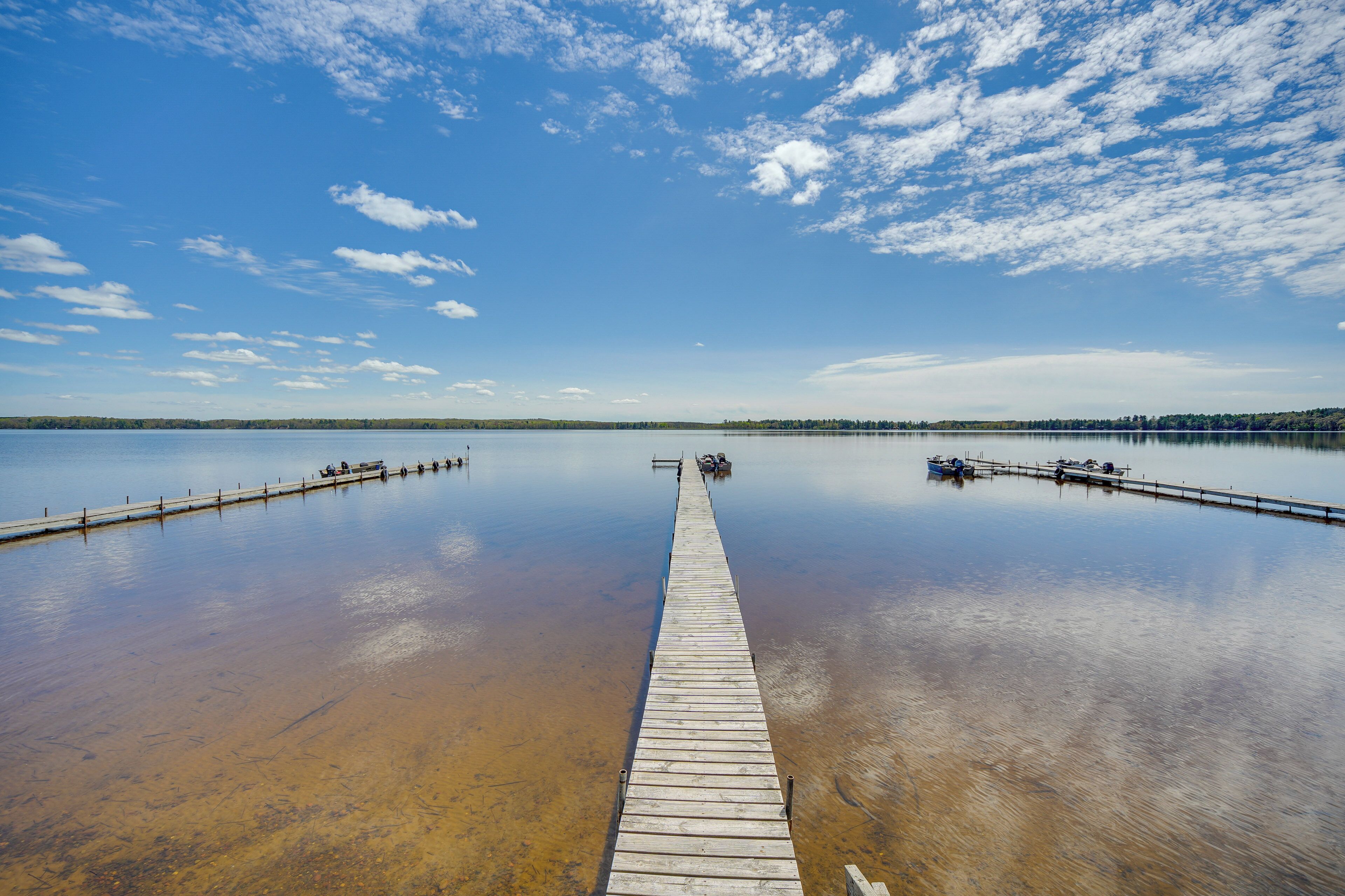 A wooden pier extending into a calm lake with clear skies.