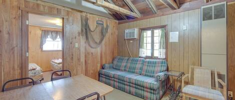A wooden interior with a plaid sofa, a dining table, and chairs.