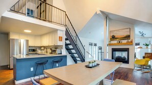 A modern kitchen with a central island, a dining area with a wooden table, and a staircase leading to an upper level. - Near Trails & Breweries: Cabin w/ Hot Tub in Breck (Breckenridge)