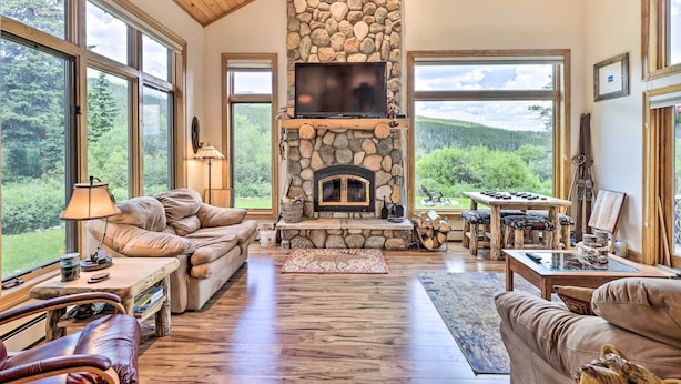 A spacious living room with a stone fireplace, large windows, and a cozy seating area.
