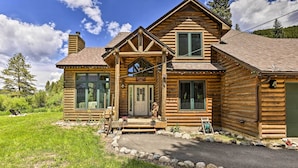 A log cabin with a front porch, large windows, and a stone pathway leading to the entrance.