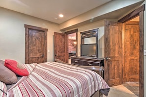 A bedroom with a bed, wooden doors, a dresser, and a TV.