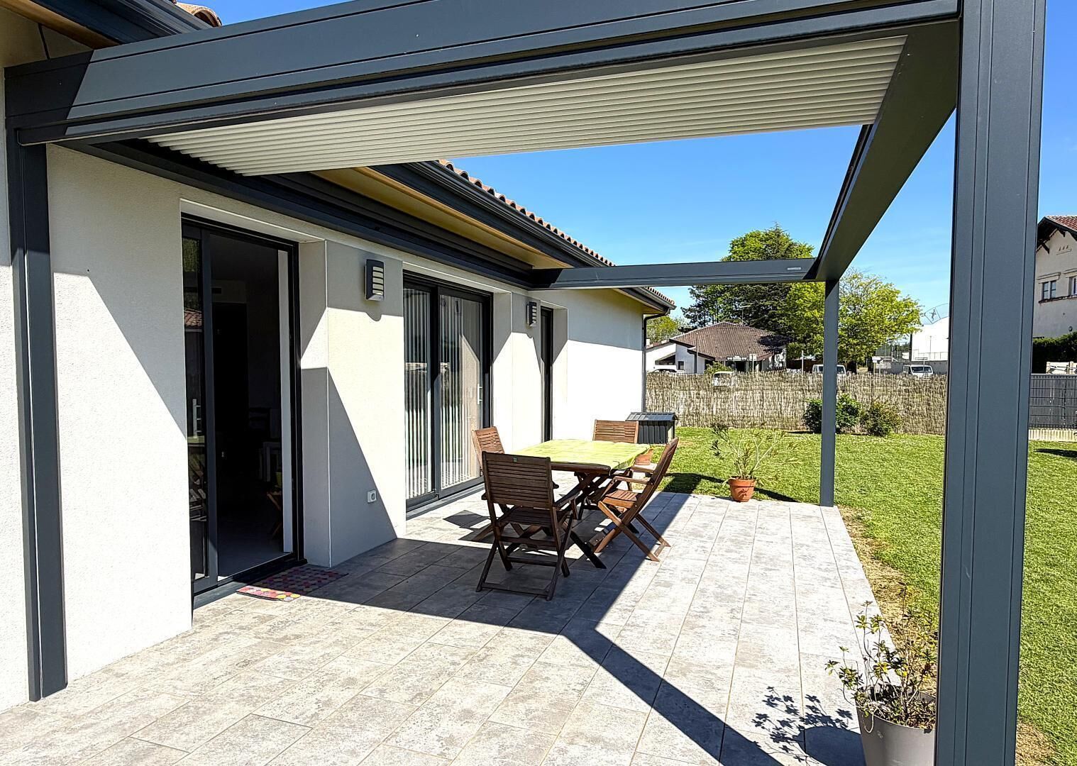 A covered patio with a table and chairs, a sliding glass door, and a view of a residential area.