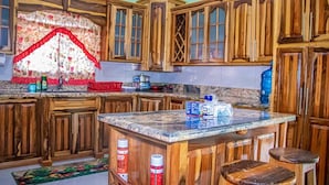 Eine Küche mit Holzausstattung, einer Granit-Arbeitsplatte und einem Fenster mit rotem Muster.