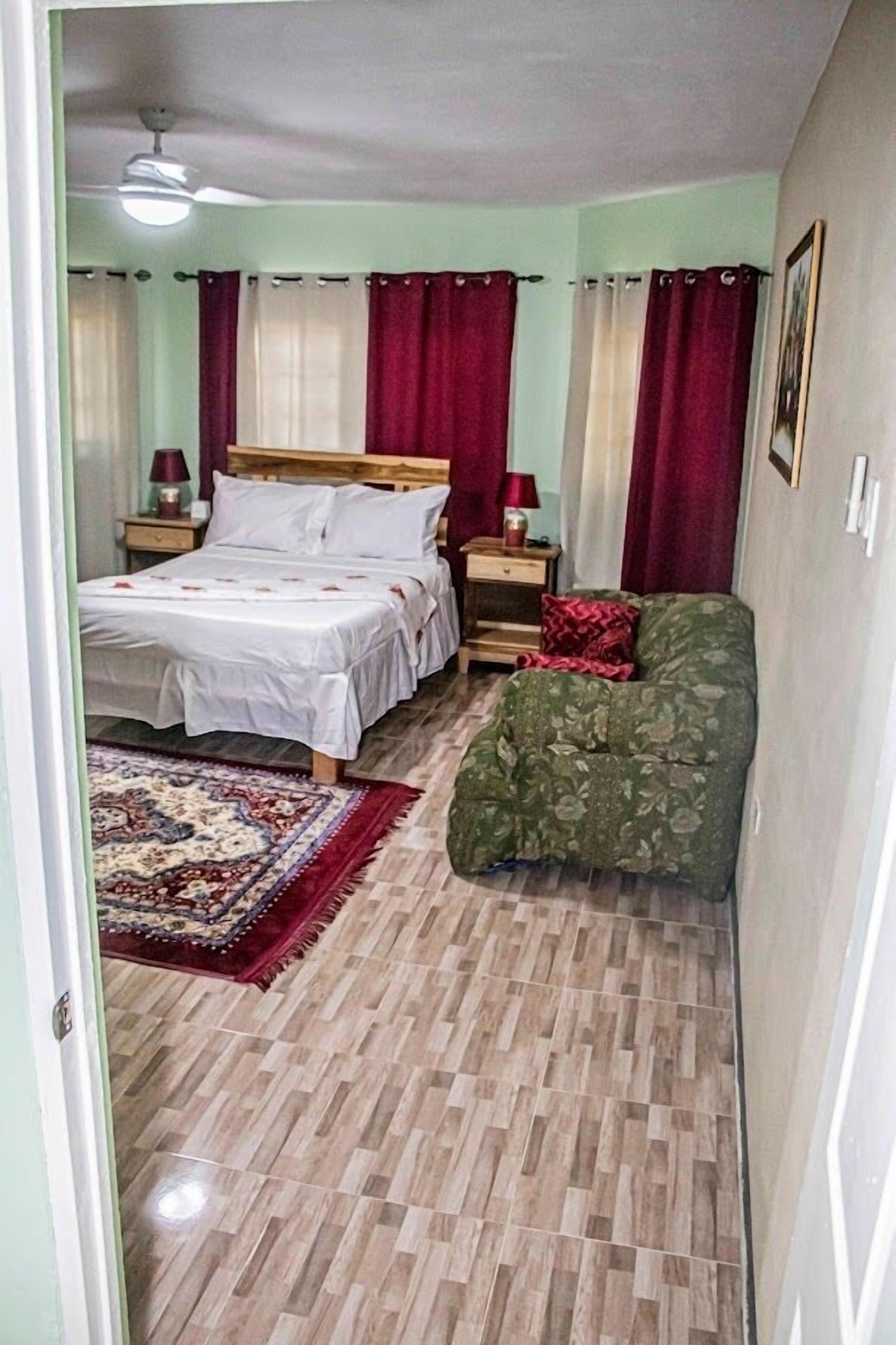 A bedroom with a bed, a nightstand, a chair, and a patterned rug.