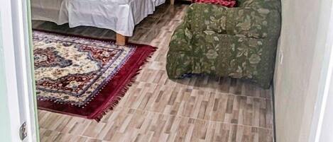 A bedroom with a bed, a nightstand, a chair, and a patterned rug.