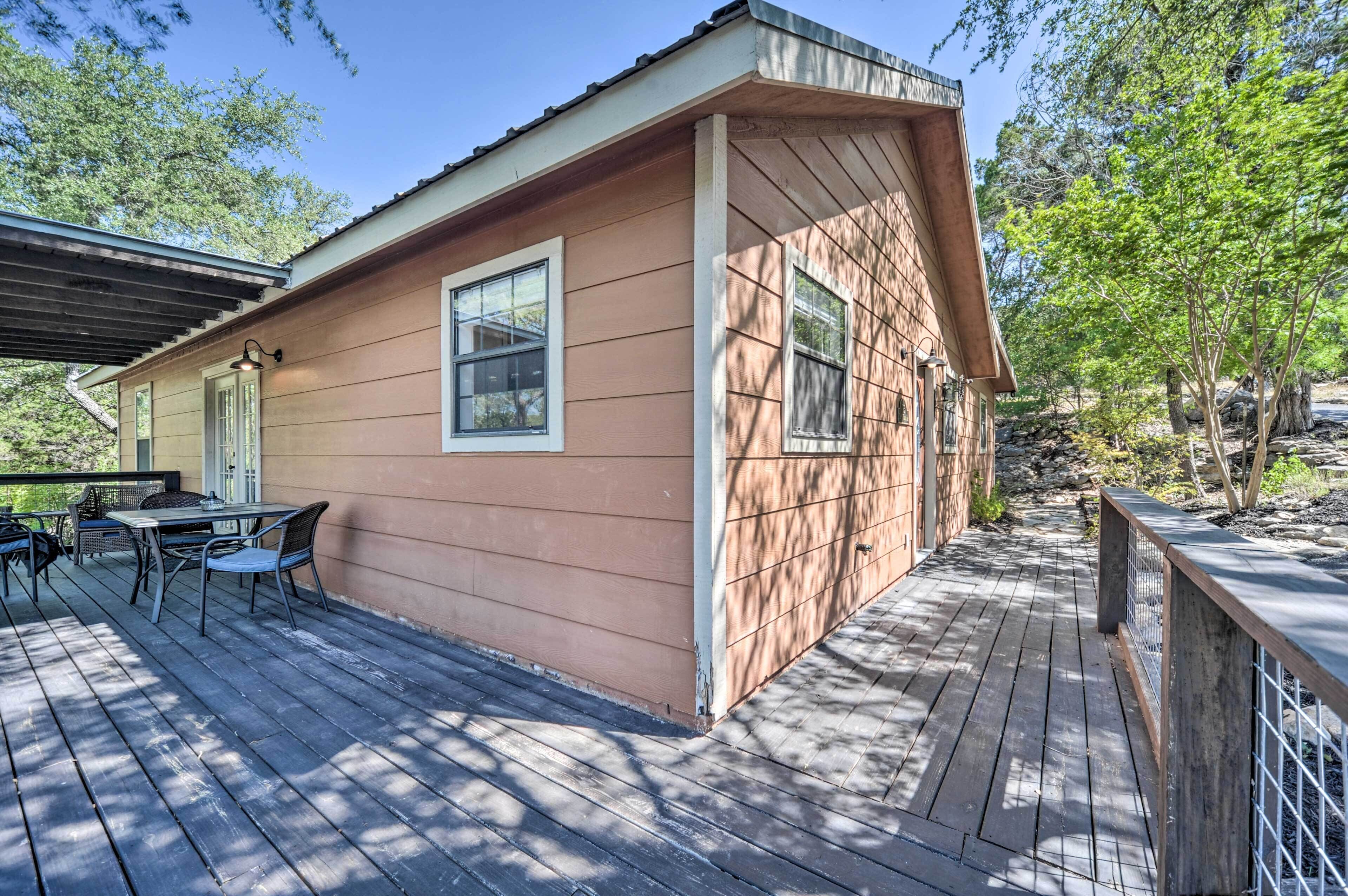 A wooden deck with a table and chairs, a covered patio, and a building with large windows.