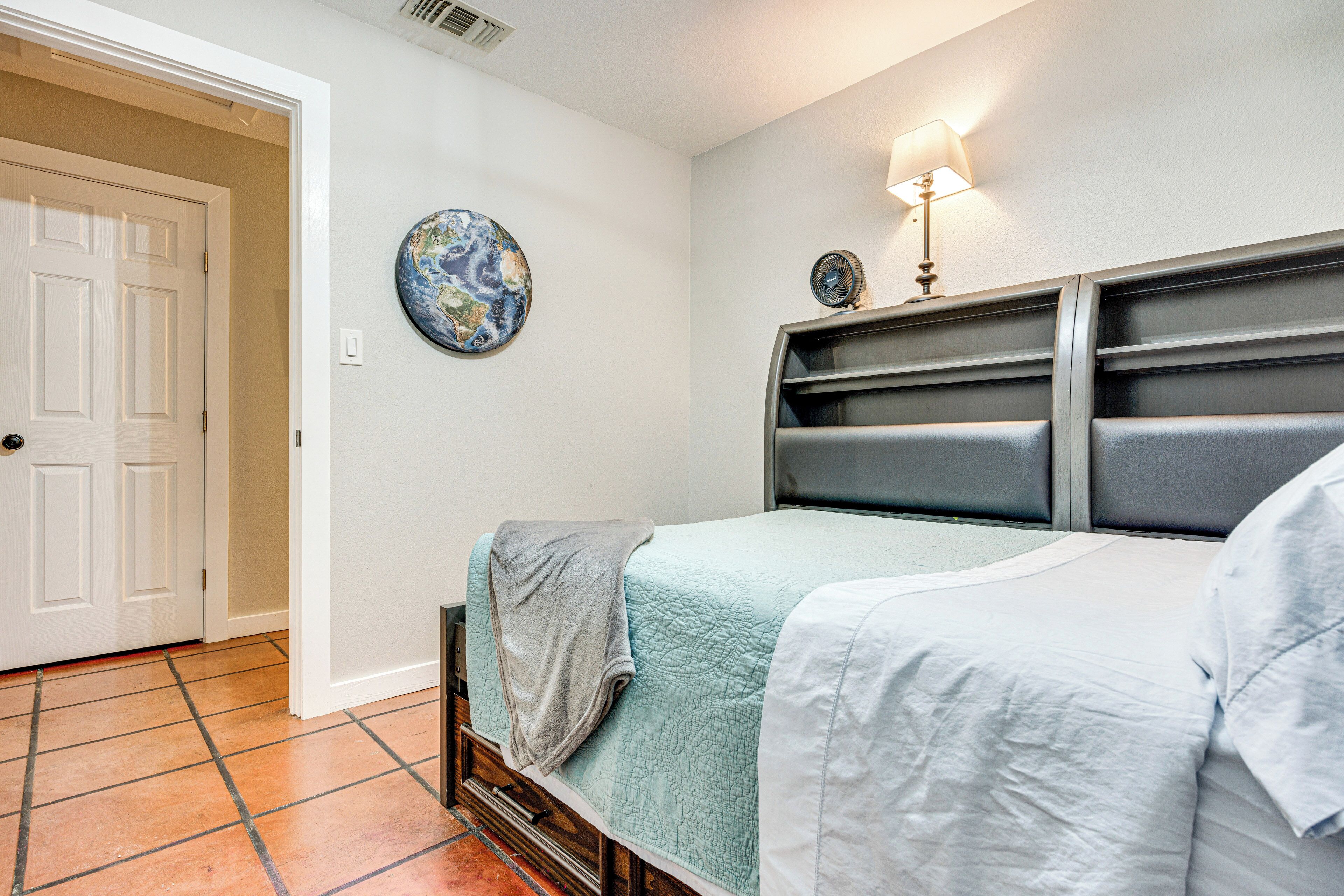 A bedroom with two beds, a globe on the wall, and a lamp.