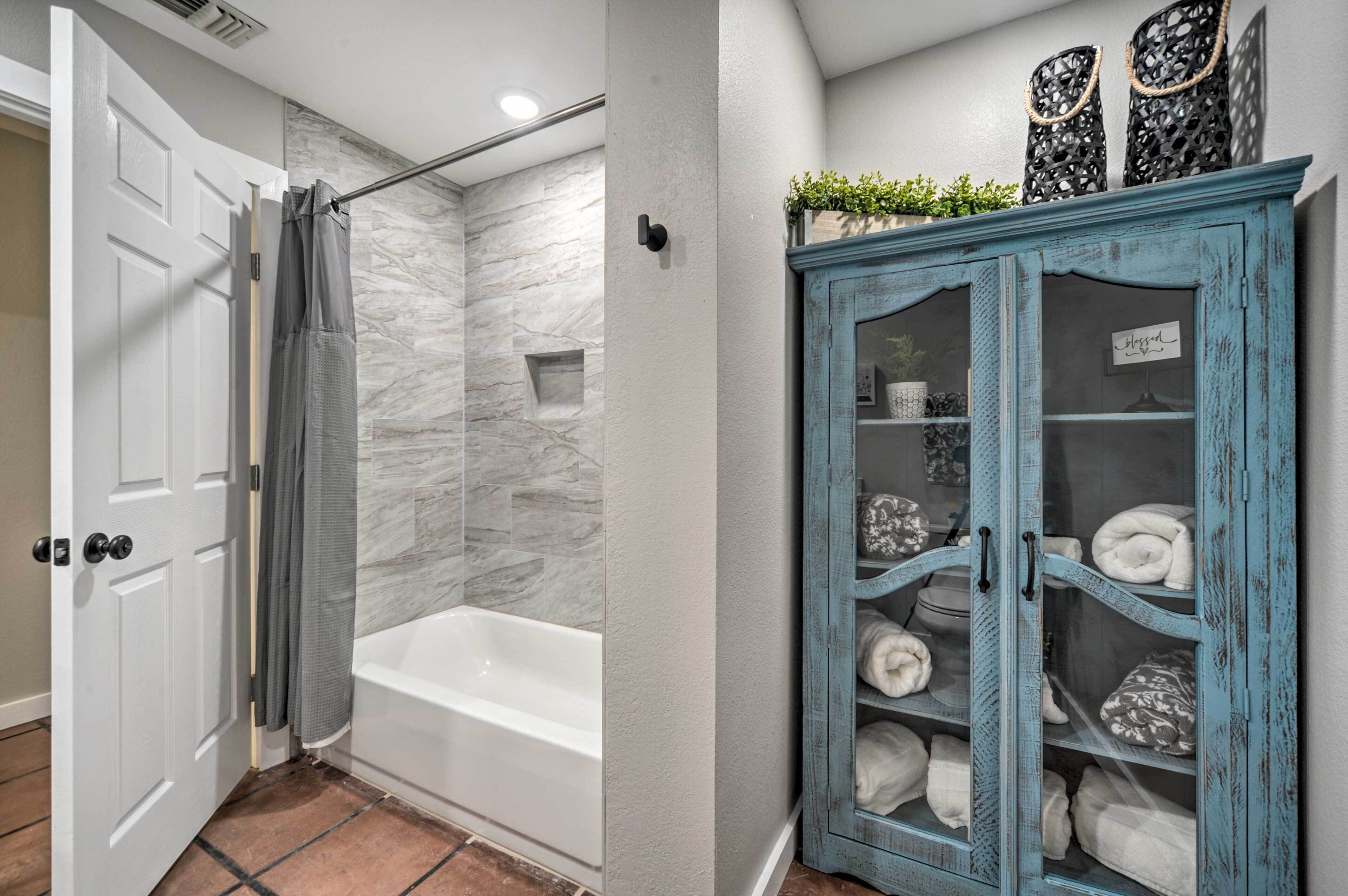 A bathroom with a white bathtub, a shower curtain, and a marble wall.