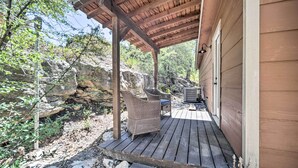 A wooden deck with wicker furniture and a stone wall backdrop.