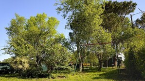 A playground with swings and a slide, surrounded by trees and grass. - Le Gemmeur - SOUSTONS (SOUSTONS)
