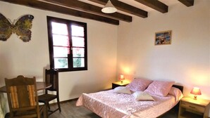 A bedroom with a bed, two bedside tables, a chair, a window, and a wall decoration. - Le Gemmeur - SOUSTONS (SOUSTONS)