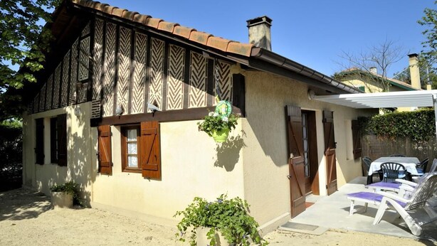 A traditional house with a tiled roof, wooden shutters, and a small garden area with a table and chairs. - Le Gemmeur - SOUSTONS (SOUSTONS)