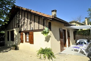 A traditional house with a tiled roof, wooden shutters, and a small garden area with a table and chairs.