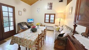 A dining area with a table set for four, a sofa, and a television. - Le Gemmeur - SOUSTONS (SOUSTONS)