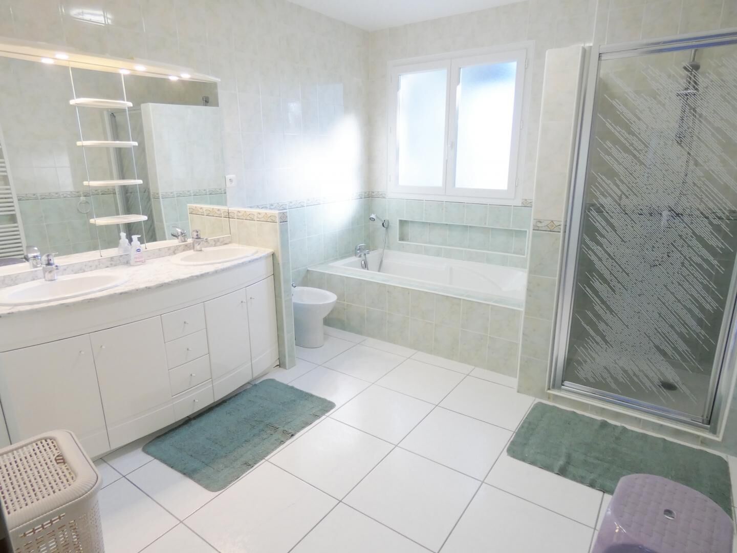 Un baño moderno con dos lavamanos, una bañera, una ducha y un espejo grande.