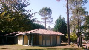 A small, single-story building with a tiled roof, surrounded by trees.