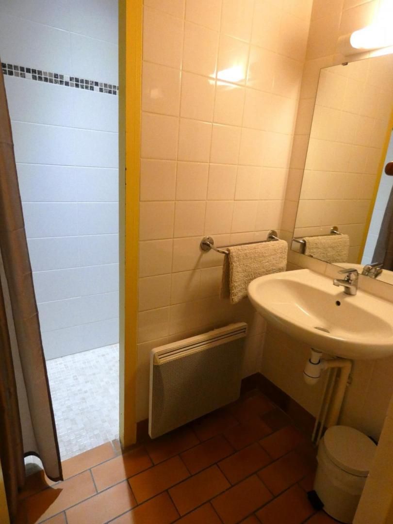 A bathroom with a white sink, a mirror, and a towel hanging on the wall.