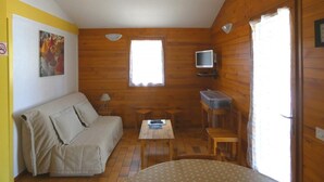 A cozy room with a sofa, a small table, a TV, and a window.