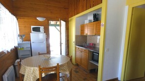 A compact kitchen with a dining table, wooden cabinets, and a microwave.