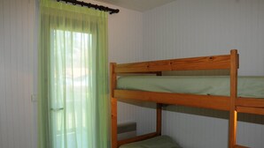 A bunk bed with a green mattress in a room with white walls and a window with green curtains. - Tamaris - Morcenx - Gîte (MORCENX)