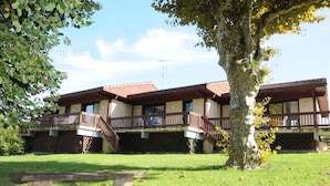 A two-story building with balconies, a staircase, and a grassy lawn. - Tamaris - Morcenx - Gîte (MORCENX)