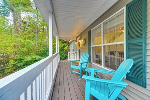 A porch with a white railing, two blue Adirondack chairs, and a window with shutters. - Conway Home w/ Hot Tub & Game Room: Near Skiing! (Conway)