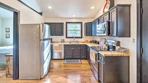 A modern kitchen with dark cabinets, stainless steel appliances, and a wooden countertop.