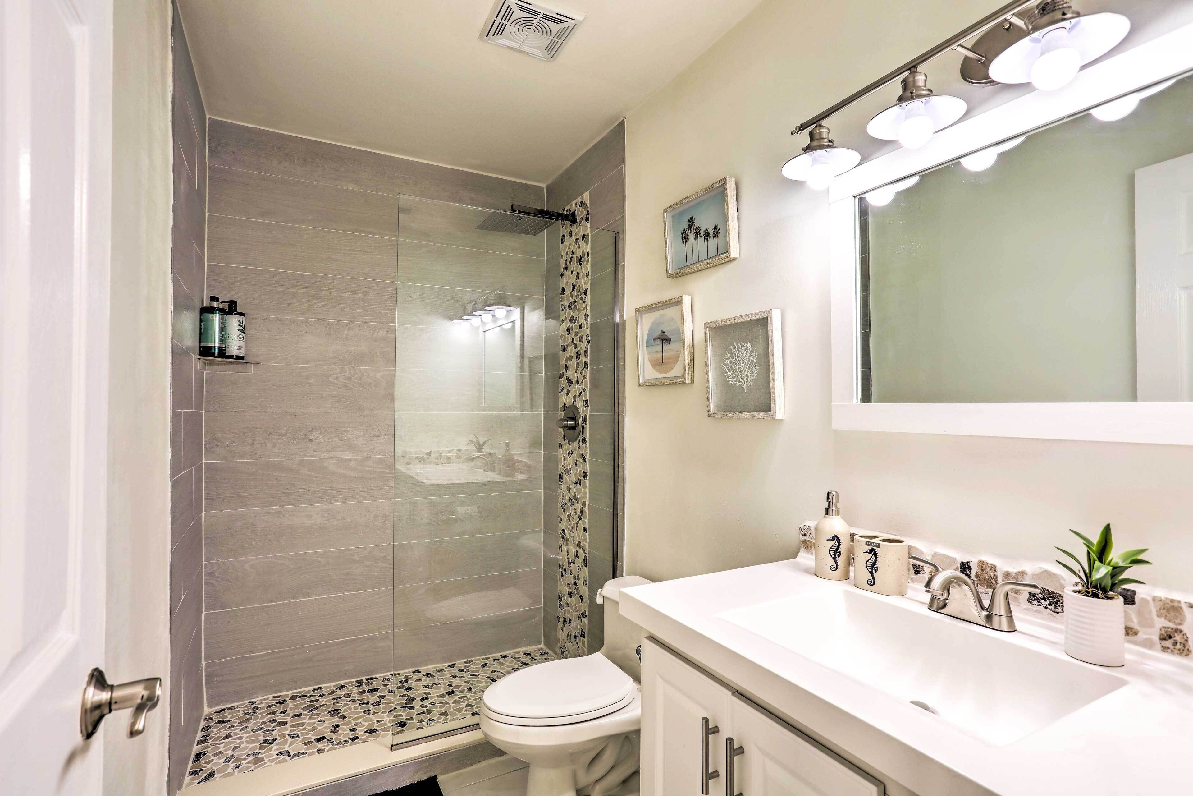 A bathroom with a shower, toilet, sink, and vanity.