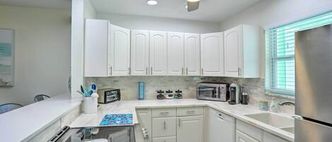 A modern kitchen with white cabinets, a stainless steel refrigerator, and a microwave.