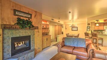 A living room with a fireplace, leather sofa, and a dining area with chairs.
