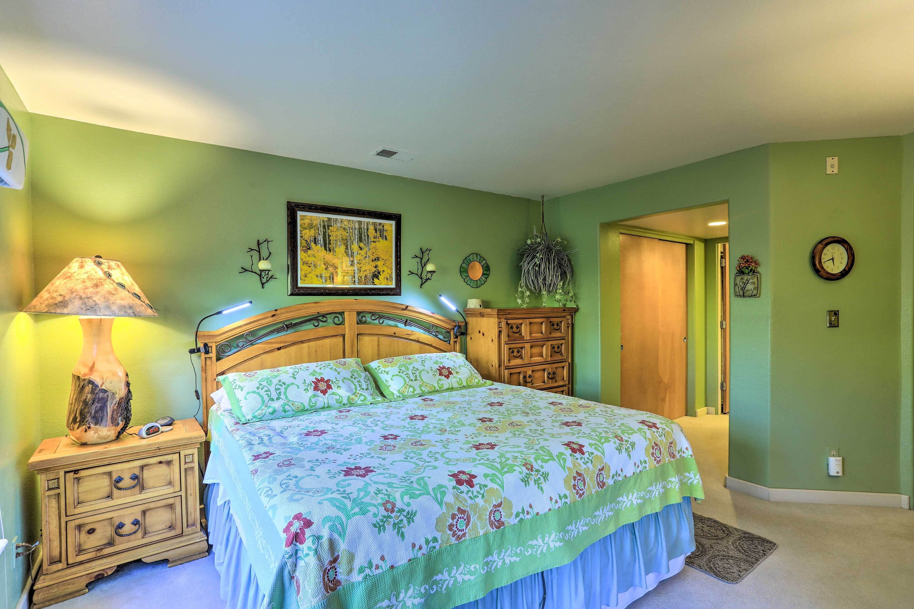 Quarto com cama, mesa de cabeceira, penteadeira e um quadro na parede.