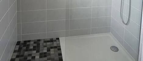 A shower area with a tiled floor, a showerhead, and a handheld shower attachment.