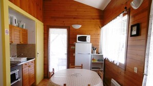 A compact kitchen with wooden walls, a dining table with a polka dot tablecloth, and basic appliances. - Les Genêts - Brocas - Gîte (BROCAS)