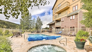 A pool area with a hot tub, lounge chairs, and a building with balconies. - Cozy Red Hawk Lodge Condo: Walk to River Run! (Keystone)