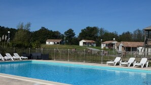 A swimming pool with white lounge chairs and a wooden play structure.