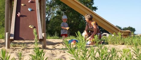 Un parque infantil con tobogán y pared de escalar.