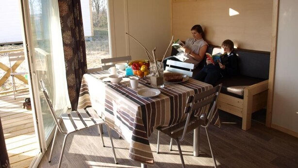 A dining area with a table set for two, a sofa, and a view of the outdoors.