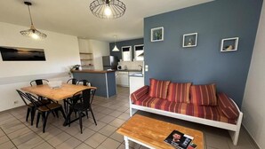 En moderne opholdsstue med spiseplads, sofa og et køkken i baggrunden.
