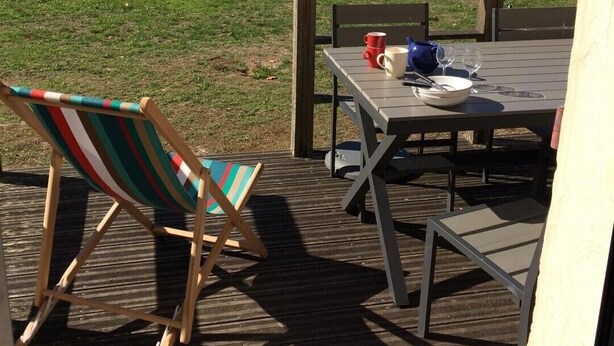 En træterrasse med bord og stole med udsigt over en sø.