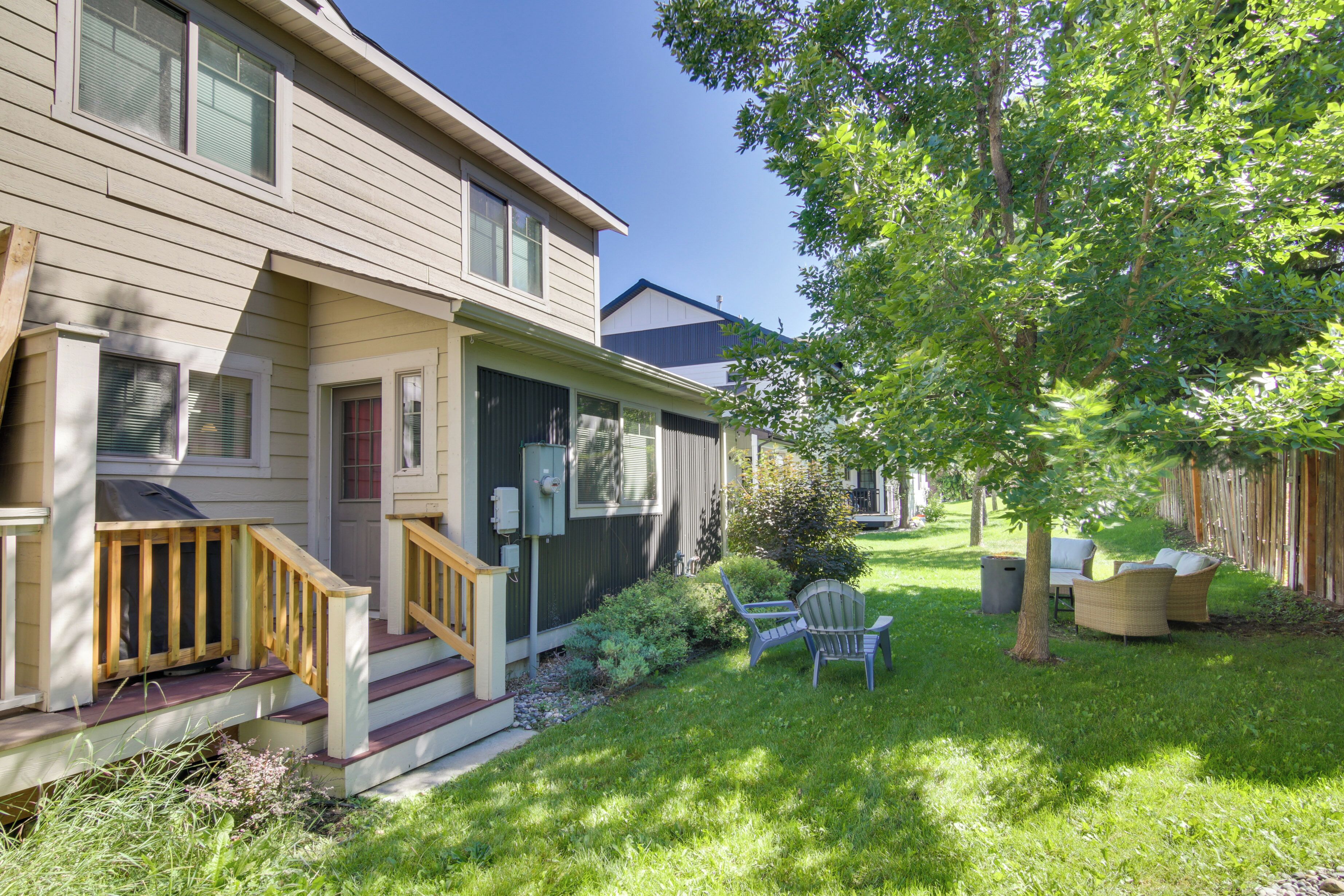 A two-story house with a front porch, a small garden with a lawn, and outdoor furniture.