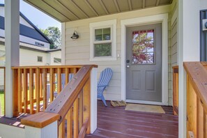 A wooden deck with a railing, a blue Adirondack chair, and a gray door with a window. - 'heart of Bozeman' Townhome w/ Patio Near MSU (Bozeman)